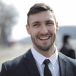 Cheerful businessman outdoors in formal attire, radiating confidence and approachability.