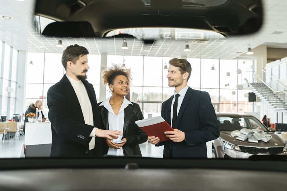 Car buyers discussing car buying options with a salesperson at a dealership before calling CarDealHero to hire them for car buying concierge services