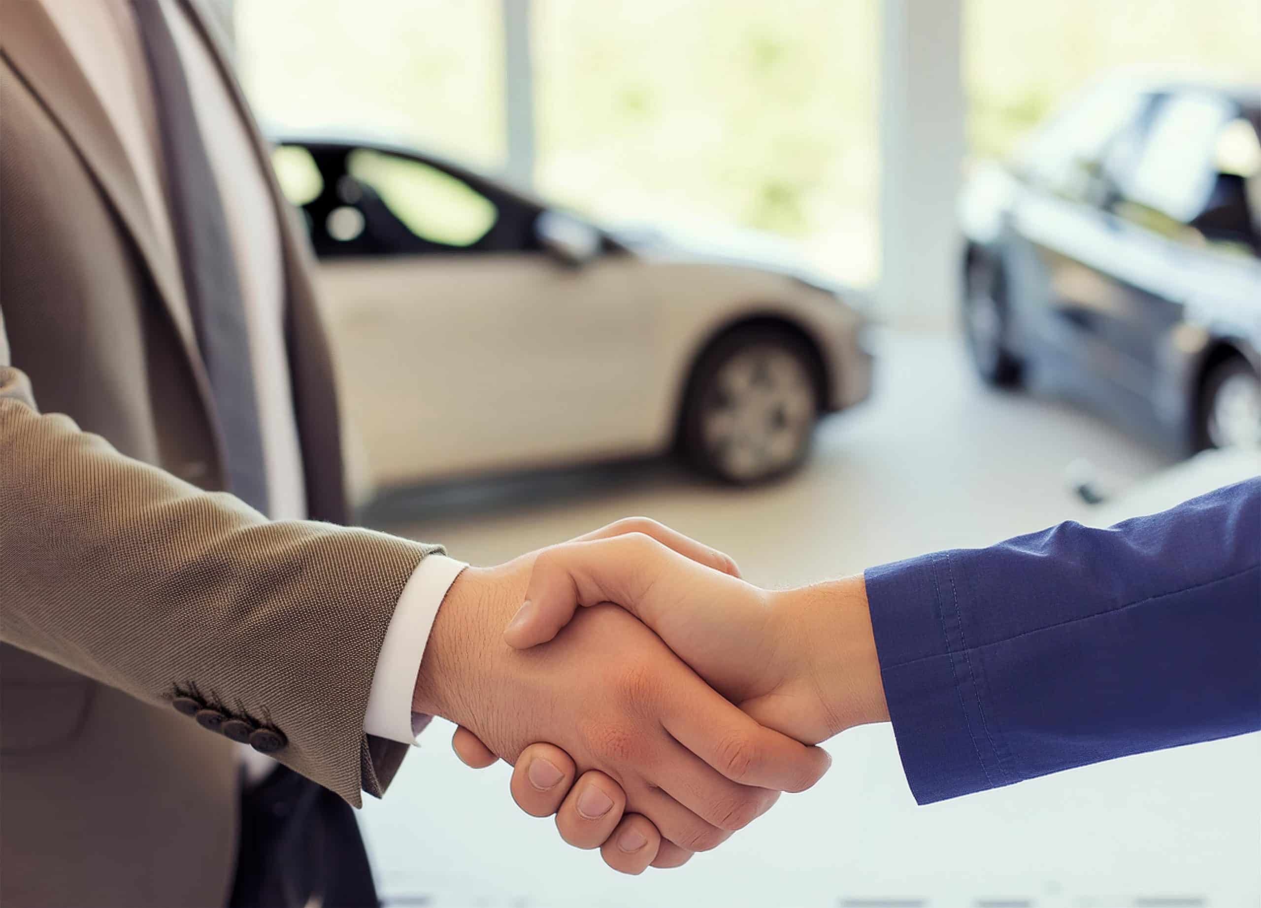 CarDealHero’s concierge team researching and negotiating the best vehicle deals for clients nationwide shaking hands with dealership sales person